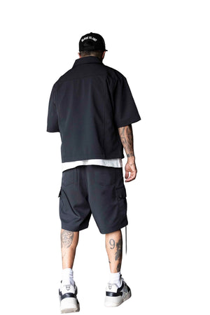 Person wearing a black shirt and shorts in a minimalistic room.
