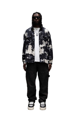Person wearing a tie-dye jacket and black pants in a modern interior setting