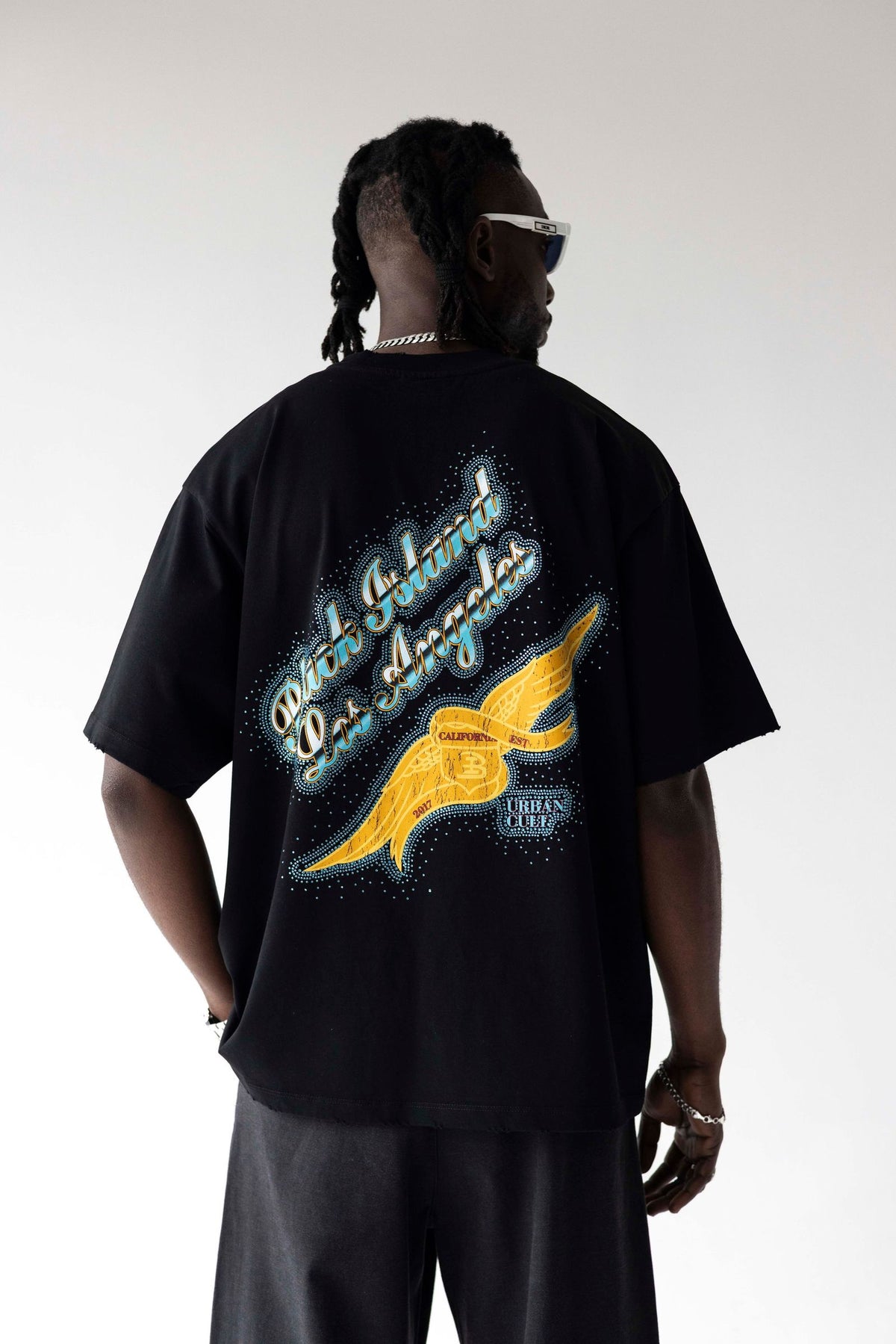Person wearing a black t-shirt with a colorful design on the back against a white background
