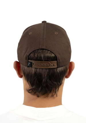 Brown cap worn by a person on a white background