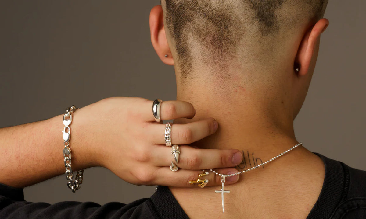 Person wearing multiple rings and a necklace with a neutral background