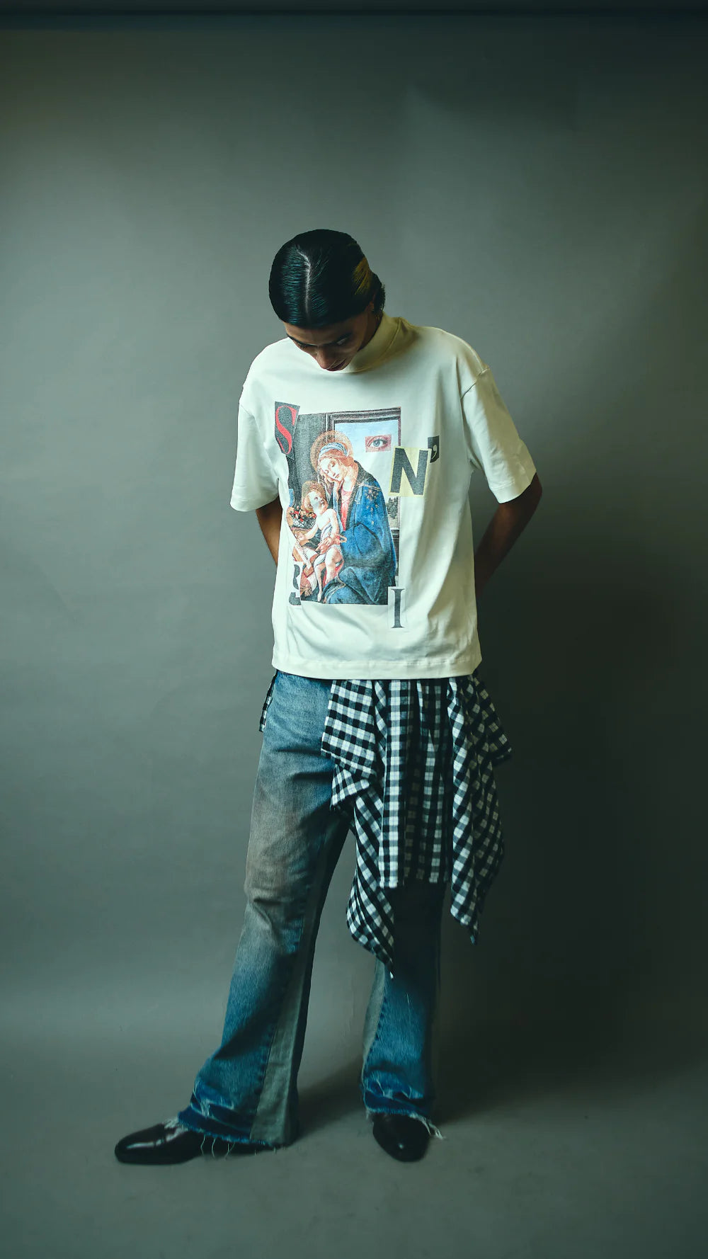 Person wearing a graphic t-shirt and checkered pants on a gray background