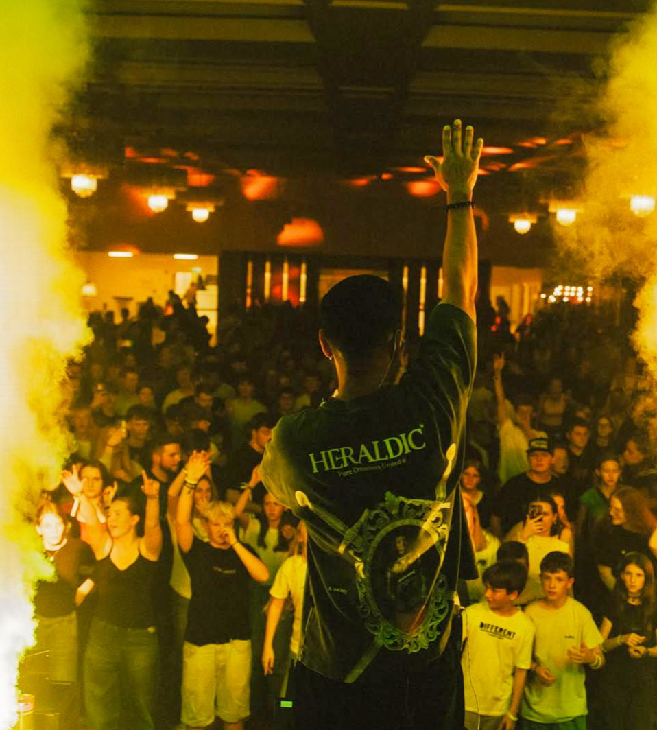 Gawvi with 'Heraldic' shirt in front of a crowd with yellow smoke effect