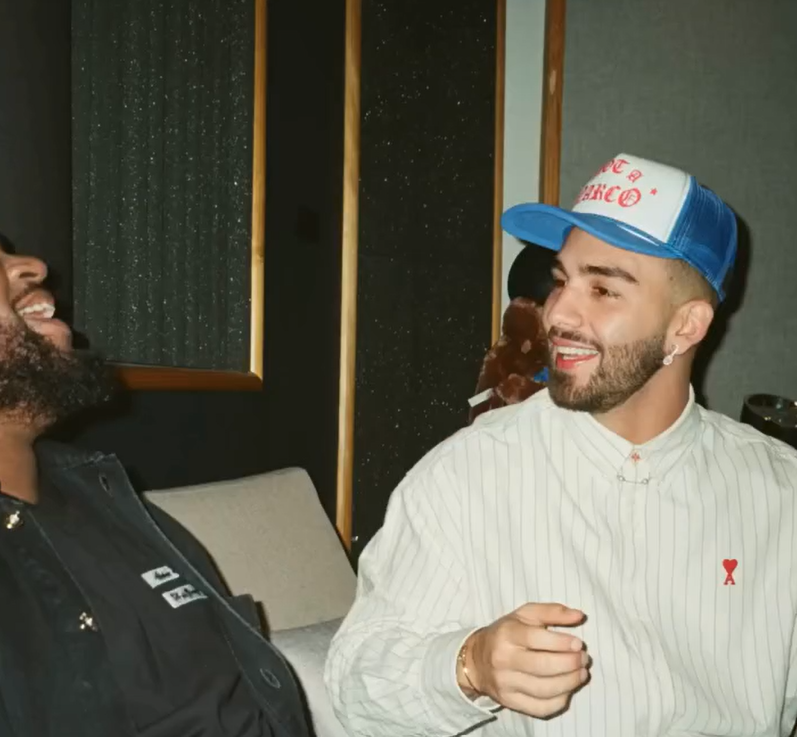 Two men are engaged in a conversation in a room with soundproofing panels. Not a Narco Hat