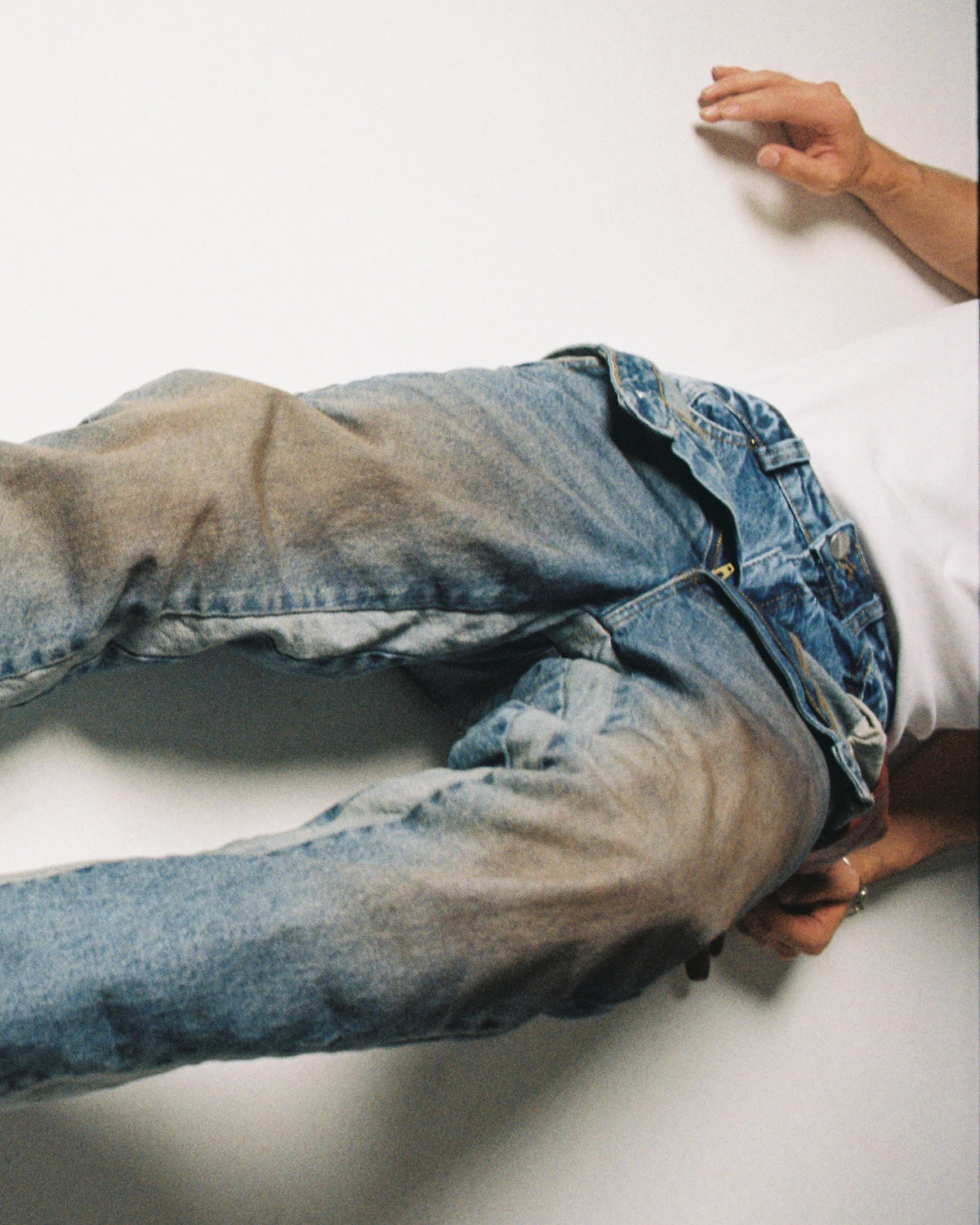 Person wearing blue jeans and a white shirt on a white background